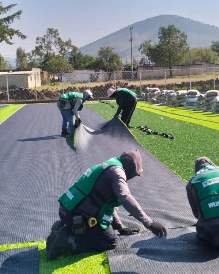 Cuánto cuesta poner pasto sintético: cuadrilla de Sportmaster instalando pasto deportivo en una cancha, precio por m² instalado