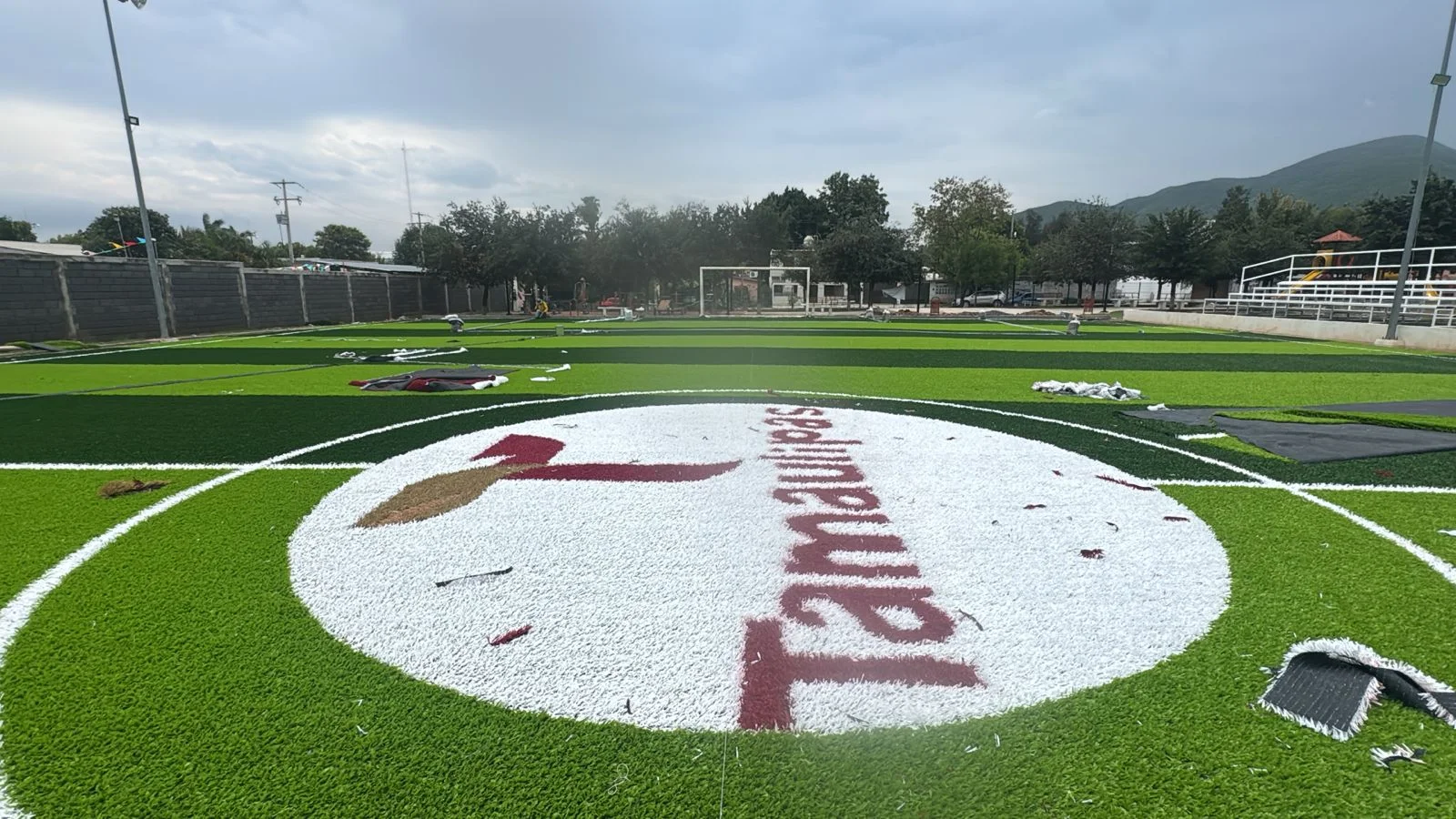 Logotipo integrado en el pasto sintético de una cancha, cortado e insertado en el pasto