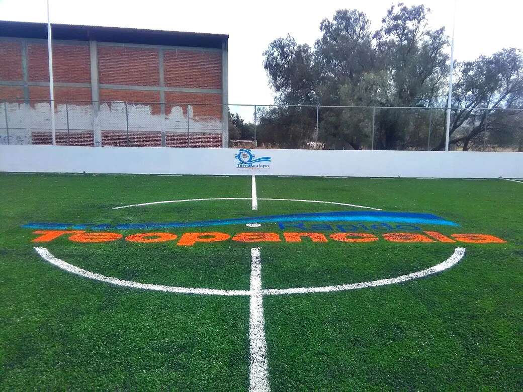 Nombre Teopancala insertado en el círculo central de una cancha de pasto sintético, vista frontal desde la línea media