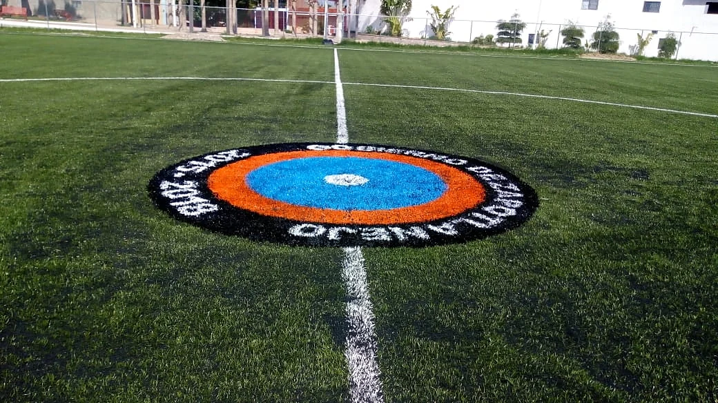 Escudo circular del Gobierno de Zapotlanejo en azul, naranja y negro insertado en el círculo central de la cancha
