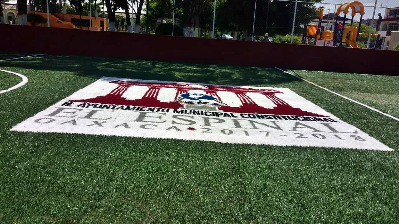 Escudo del H. Ayuntamiento de El Espinal, Oaxaca, 2017-2018, insertado en pasto sintético en guinda y blanco