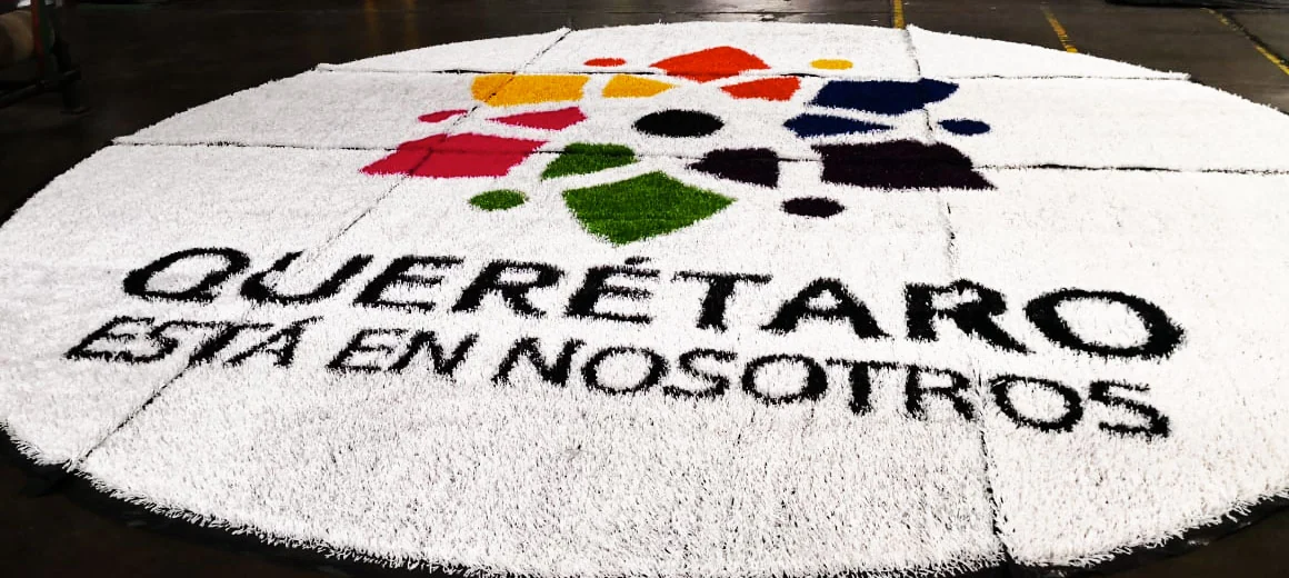 Logotipo Querétaro está en nosotros del Gobierno del Estado de Querétaro, multicolor sobre pasto sintético blanco, armado en taller