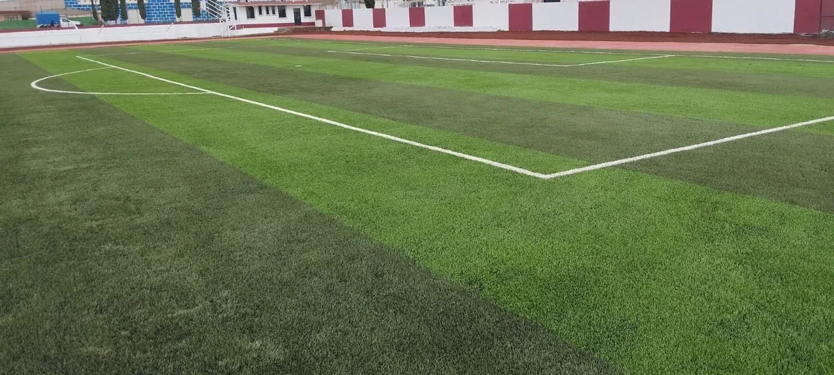 Área grande con líneas blancas insertadas en pasto sintético a franjas en el Campo Deportivo Chignahuapan, Puebla