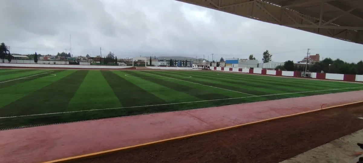 Cancha de soccer con pasto sintético vista desde las gradas techadas del Campo Deportivo Chignahuapan, Puebla