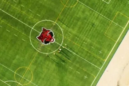 Círculo central con escudo integrado en el pasto sintético de la cancha de soccer de Arkansas State University, Querétaro