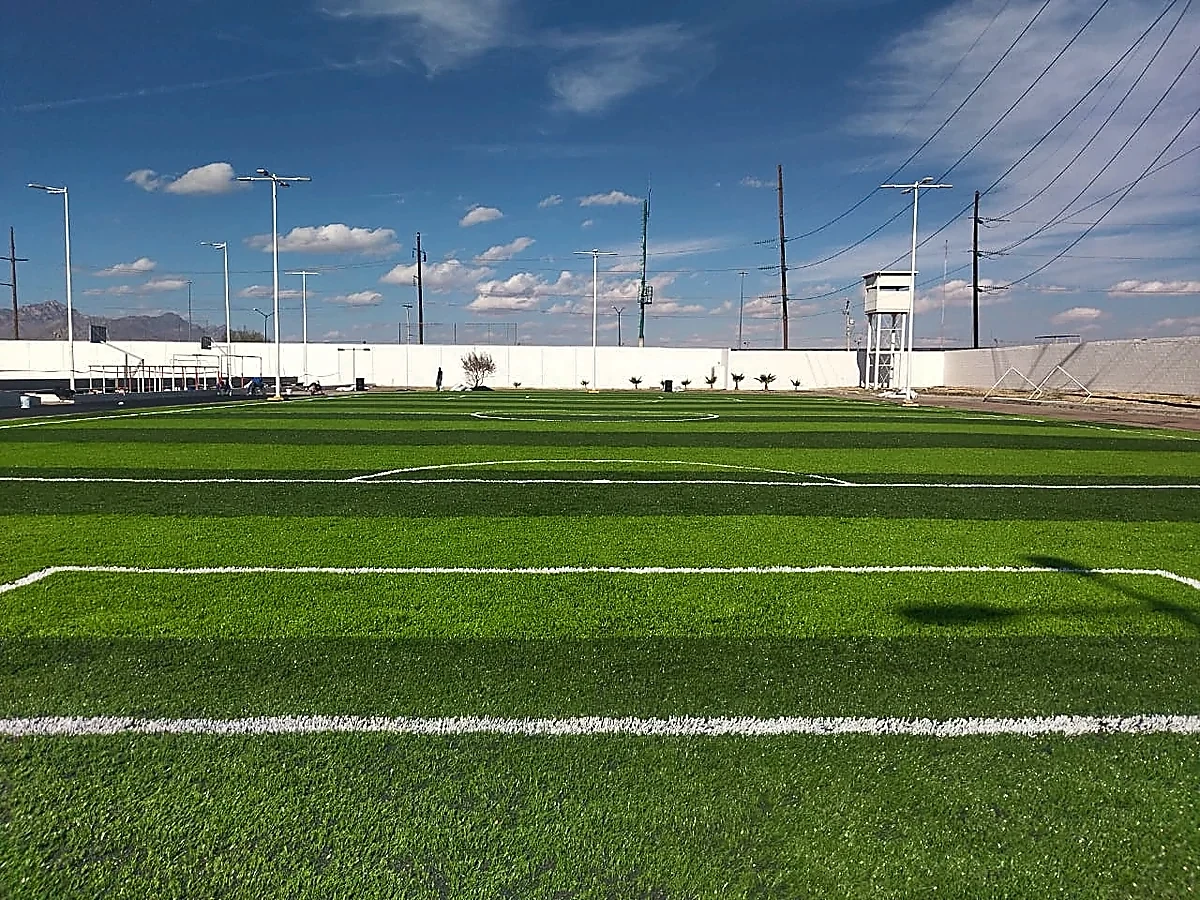 Cancha de fútbol 7 con pasto sintético en Academia de Guardia Nacional, Ciudad Juárez, Chihuahua: la cancha desde la línea lateral