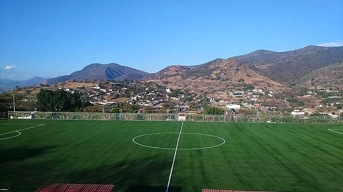 Cancha de fútbol soccer con pasto sintético en Campo deportivo de Peñoles, Apaxtla, Guerrero: vista de la cancha y su entorno