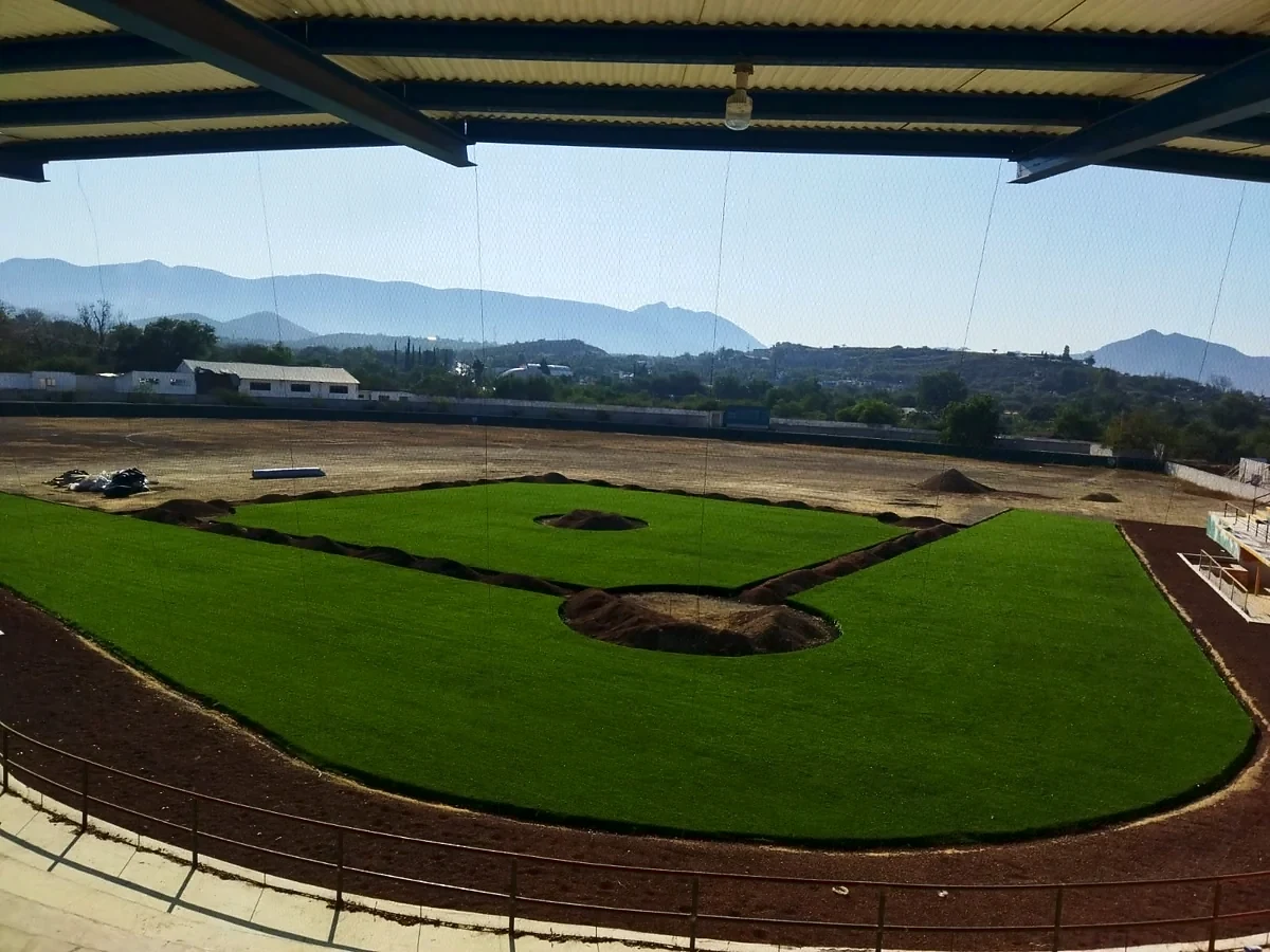 Instalación del pasto sintético del cuadro de béisbol vista desde las gradas techadas del Estadio Mineros de Zimapán