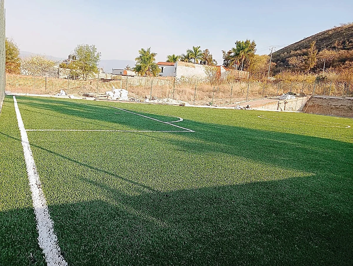 Cancha de fútbol 5 con pasto sintético en Escuela de Futbol Fénix, Zinapécuaro, Michoacán: la cancha desde la línea lateral