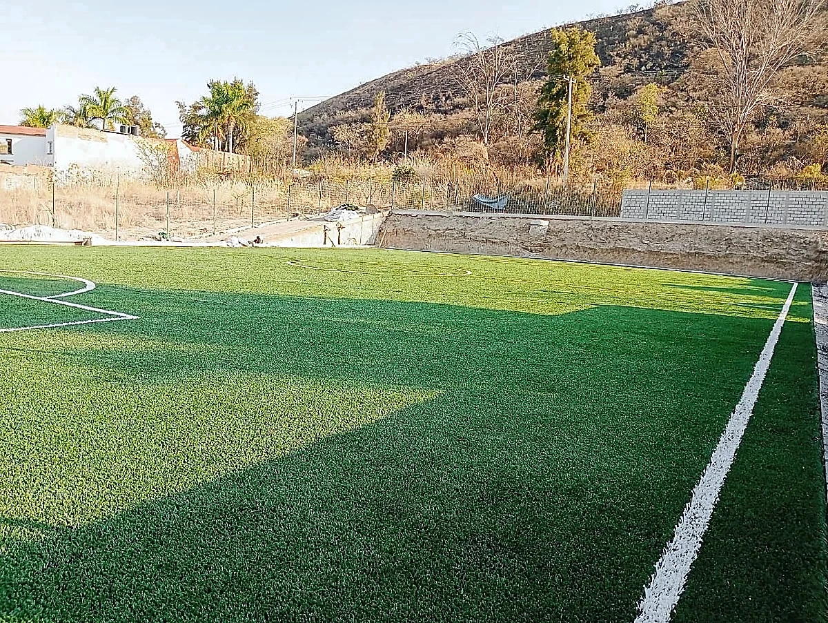 Cancha de fútbol 5 con pasto sintético en Escuela de Futbol Fénix, Zinapécuaro, Michoacán: vista de la cancha y su entorno