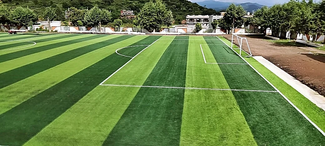 Cancha de fútbol soccer con pasto sintético en Unidad Deportiva 18 de Marzo, Tzintzingareo (Irimbo), Michoacán: la cancha desde la línea lateral