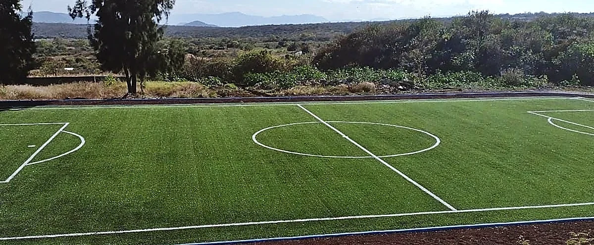 Cancha de fútbol 7 con pasto sintético en Escuela Secundaria Técnica No. 32, Tepoztlán, Morelos: la cancha desde la línea lateral