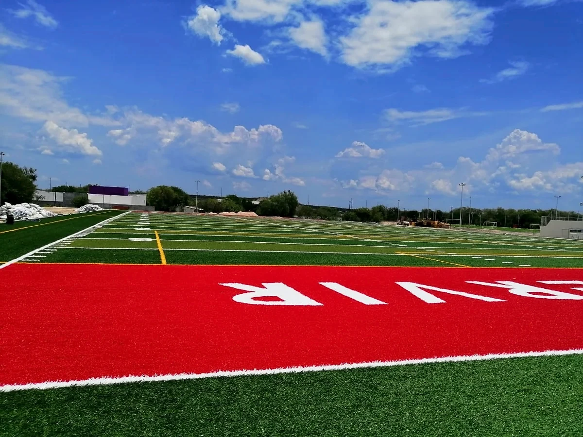 Zona de anotación en pasto sintético rojo con letras integradas en el campo de fútbol americano de Pesquería, Nuevo León