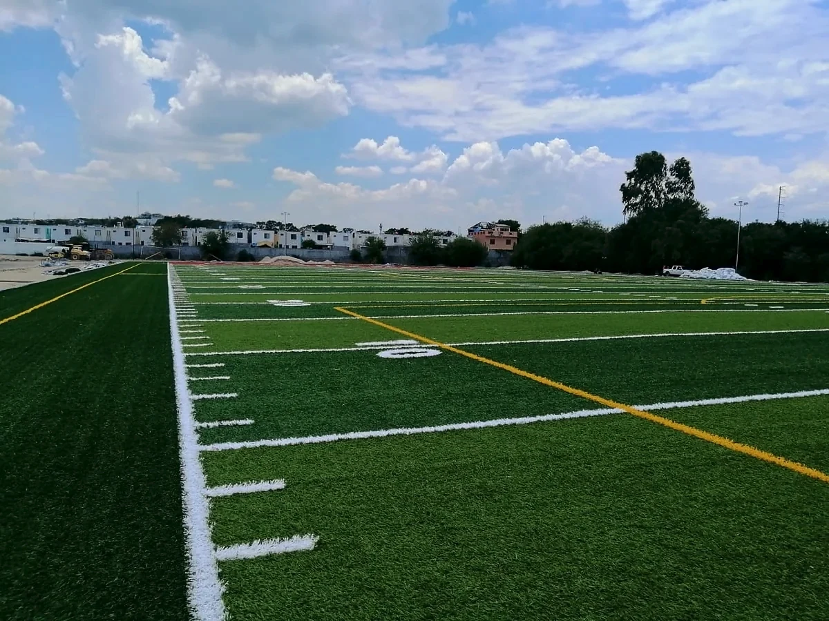 Línea lateral con yardas y la zona de anotación roja al fondo en el campo de americano de Pesquería, Nuevo León