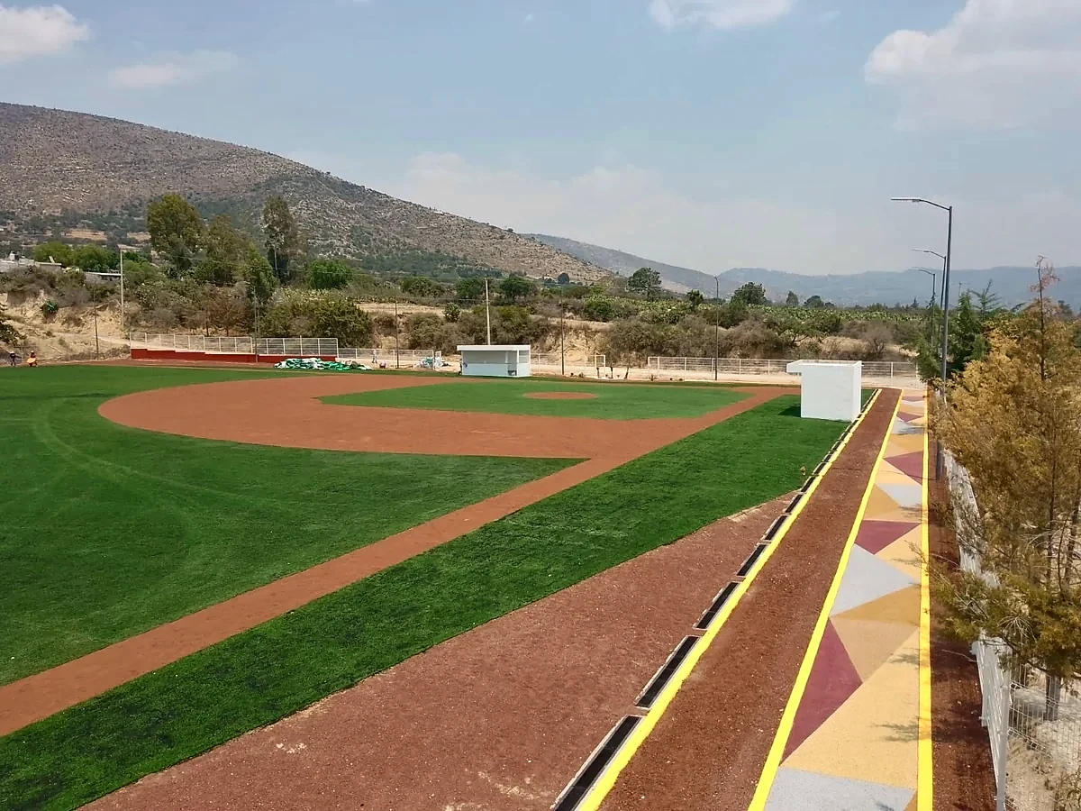 Campo de béisbol con pasto sintético y andador perimetral en el Campo Felipe Ángeles, Santiago Tenango, Puebla