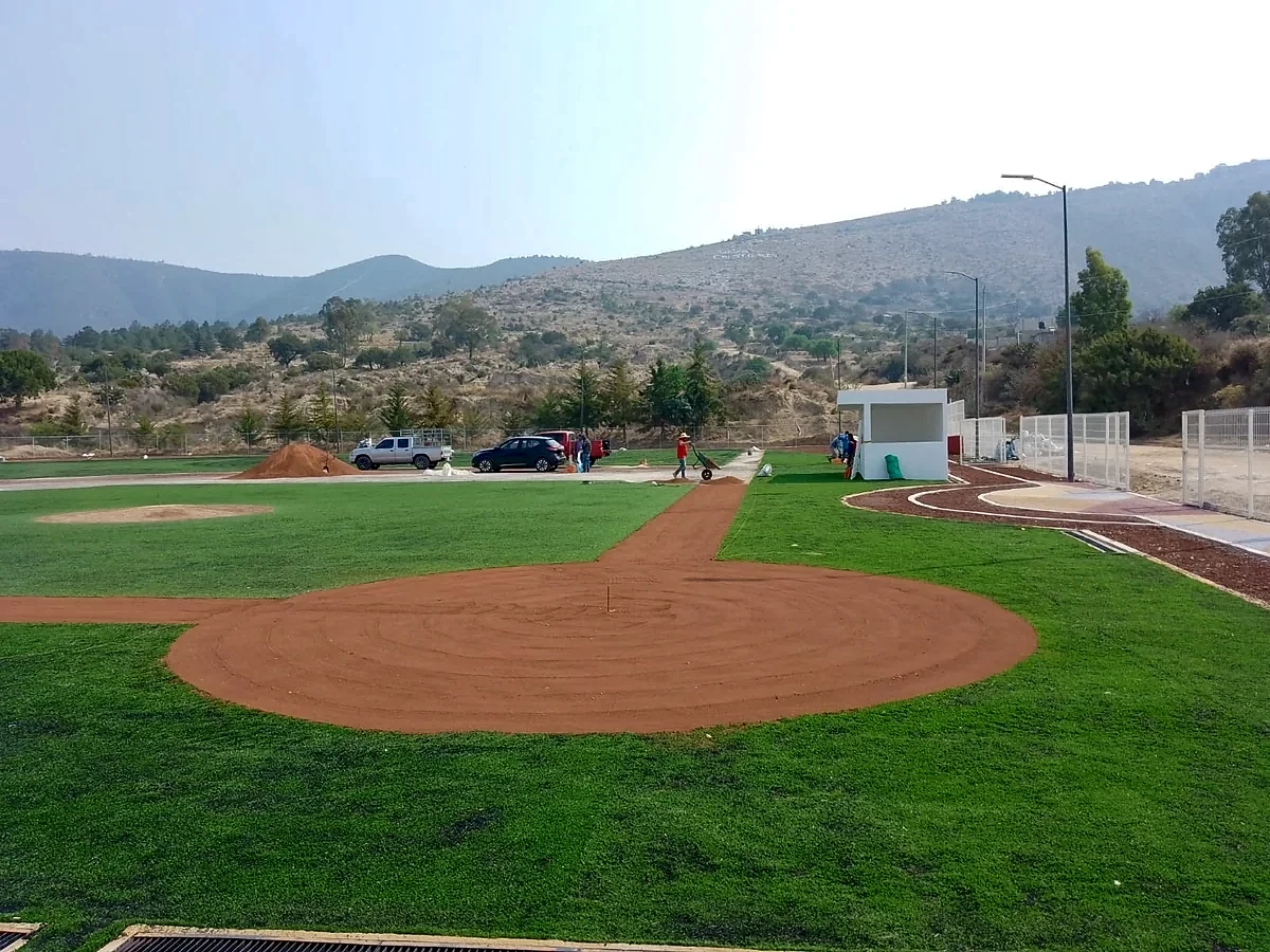 Cuadro del campo de béisbol con pasto sintético y montículo del lanzador durante la instalación en Santiago Tenango, Puebla