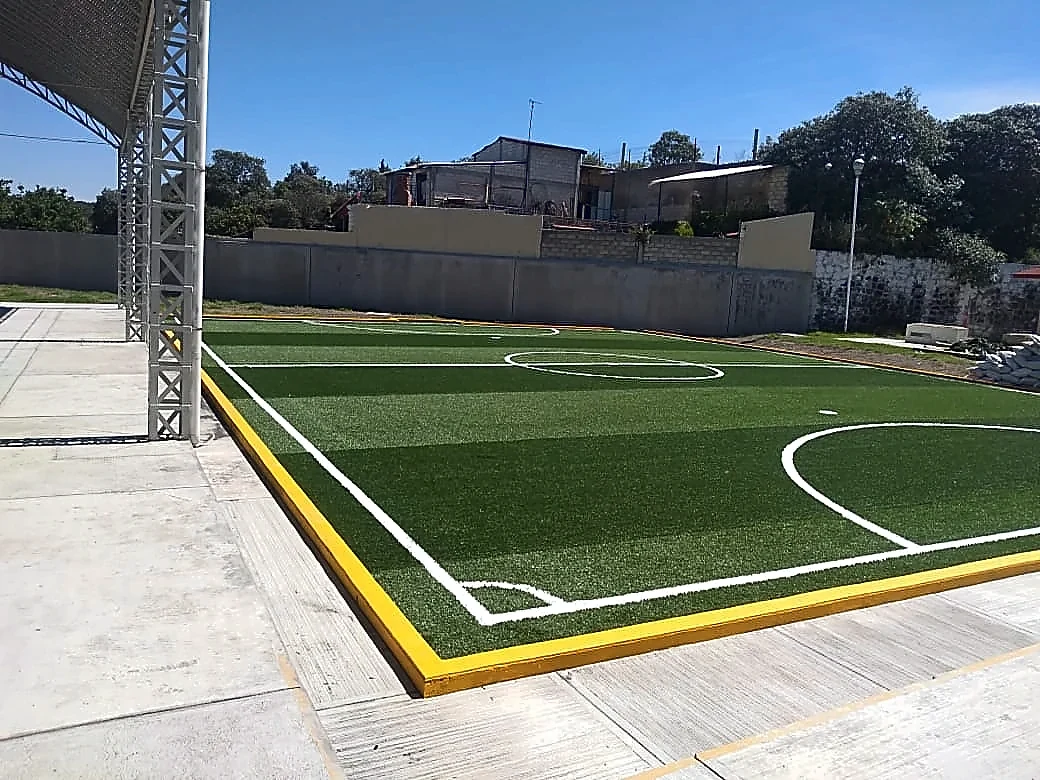 Cancha de fútbol 5 con pasto sintético en Secundaria Lic. Álvaro Gálvez, San Nicolás de los Ranchos, Puebla: la cancha desde la línea lateral