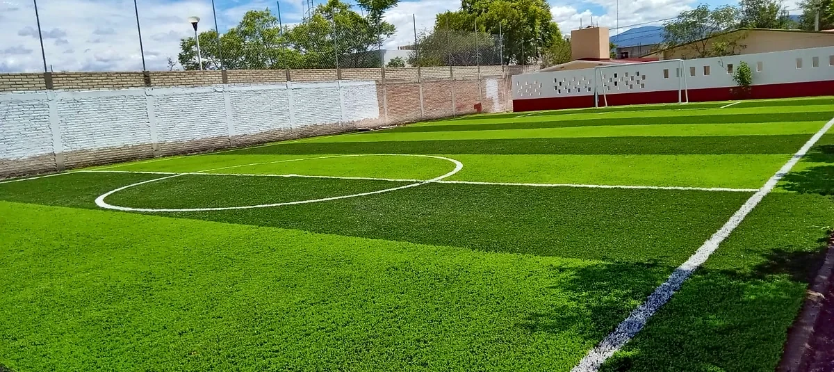 Cancha de fútbol 7 con pasto sintético en Telesecundaria Martín Luther King, San José Miahuatlán, Puebla: líneas de juego insertadas en el mismo pasto