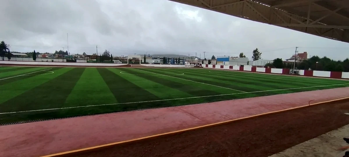 Cancha de soccer con pasto sintético vista desde las gradas techadas del Campo Deportivo Chignahuapan, Puebla