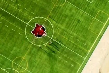 Círculo central con el escudo de Arkansas State University en pasto sintético, Querétaro