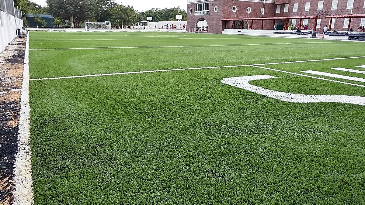 Campo de fútbol americano con pasto sintético en Colegio Álamos, Cancún, Quintana Roo: pasto sintético deportivo recién cepillado