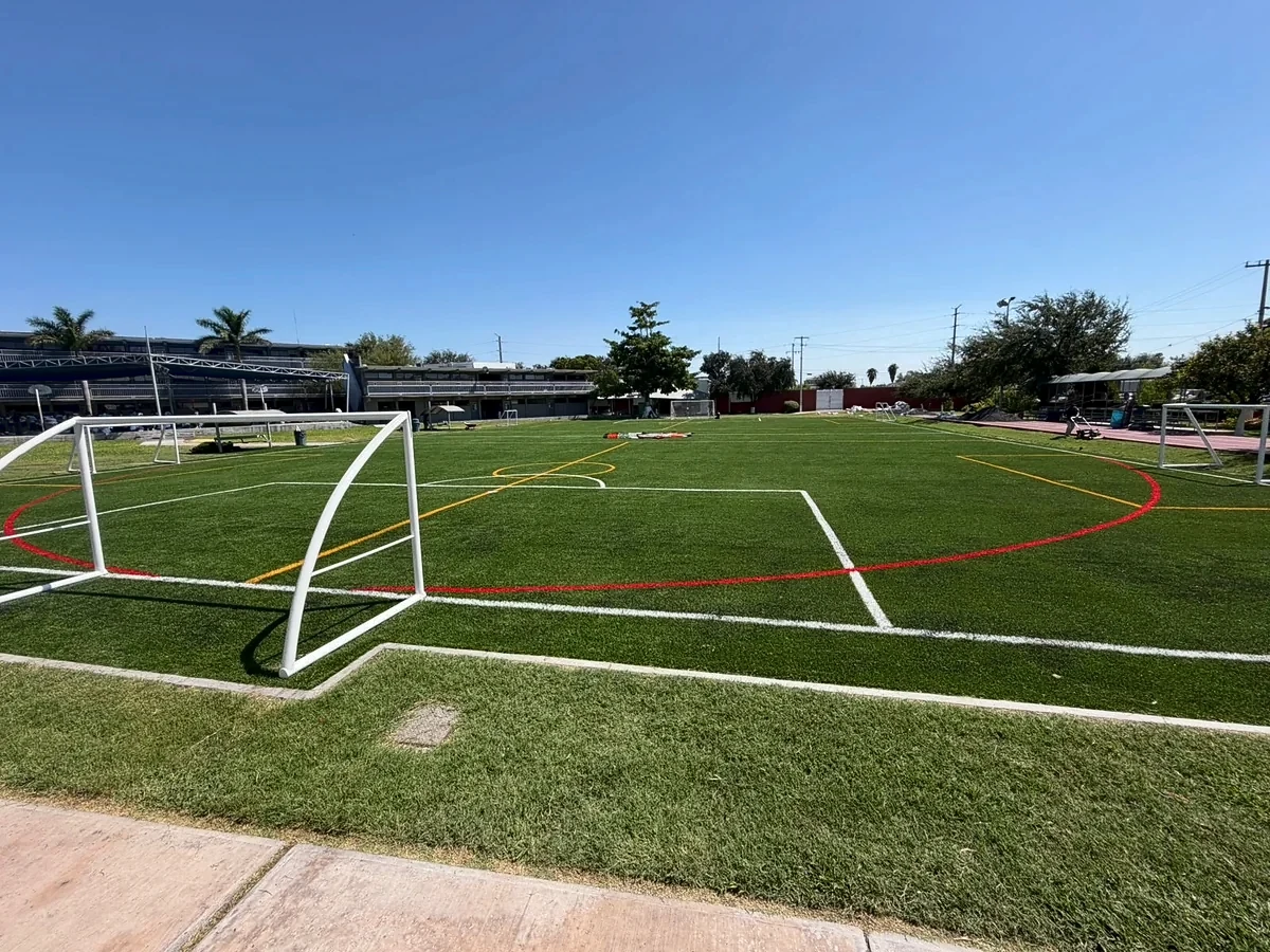 Vista general de la cancha de pasto sintético del Colegio Mexicano en Reynosa con portería y líneas en tres colores