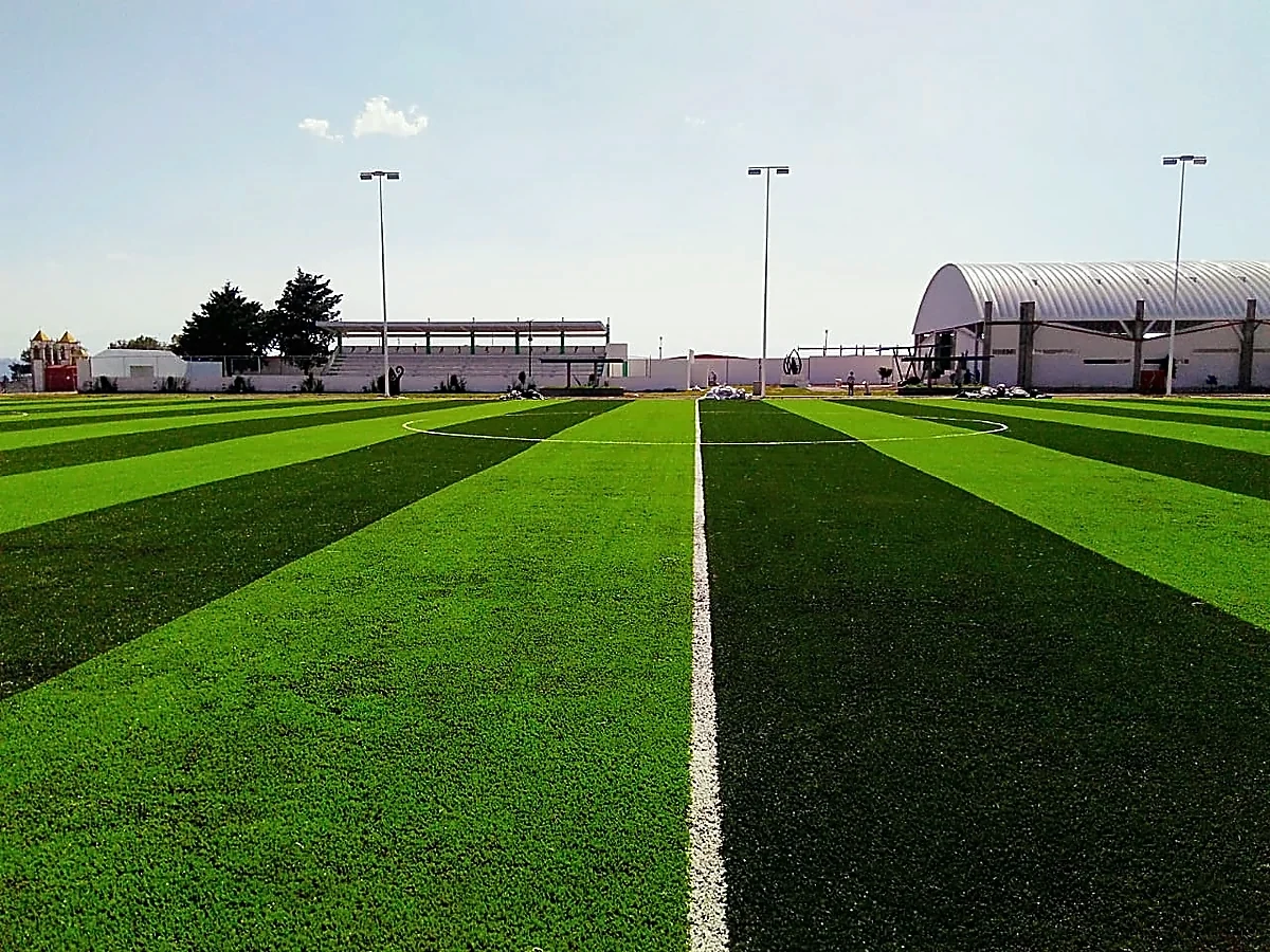 Cancha de fútbol soccer con pasto sintético en Unidad Deportiva Texoloc, Tlaxcala: la cancha desde la línea lateral