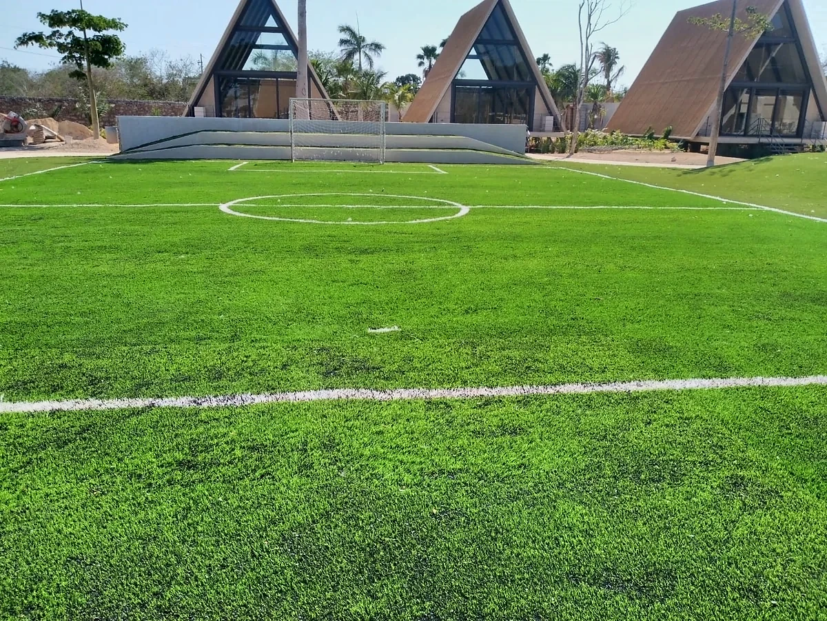 Cancha de fútbol 5 con pasto sintético en Hacienda Chichi Suárez, Mérida, Yucatán: la cancha desde la línea lateral